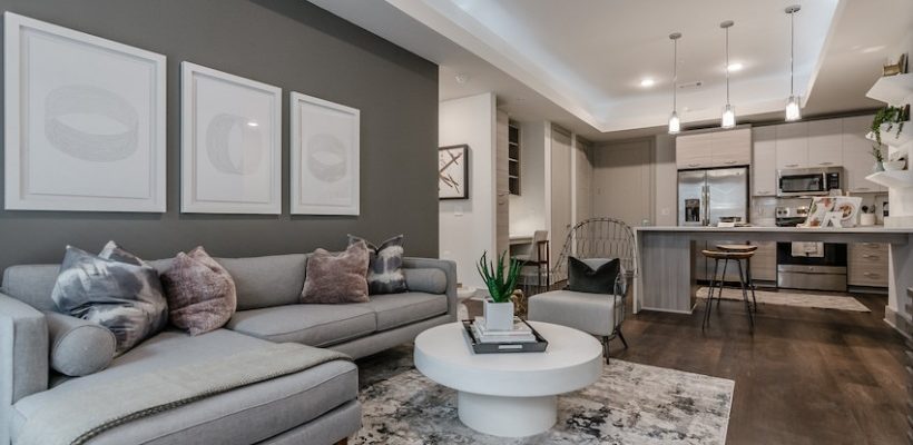 trendy grey walls, wall art, grey couch, and white round coffee table
