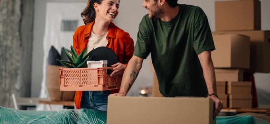 Young,Couple,Moving,Into,Their,New,Apartment,,Joyfully,Carrying,Boxes