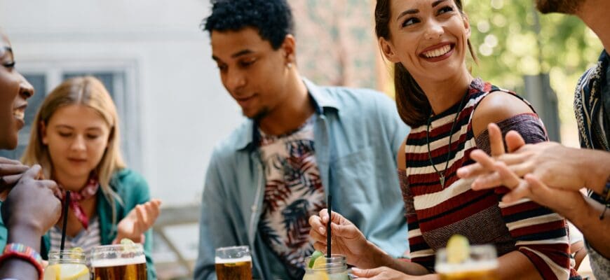 A group of people sitting with drinks at an outdoor restaurant table