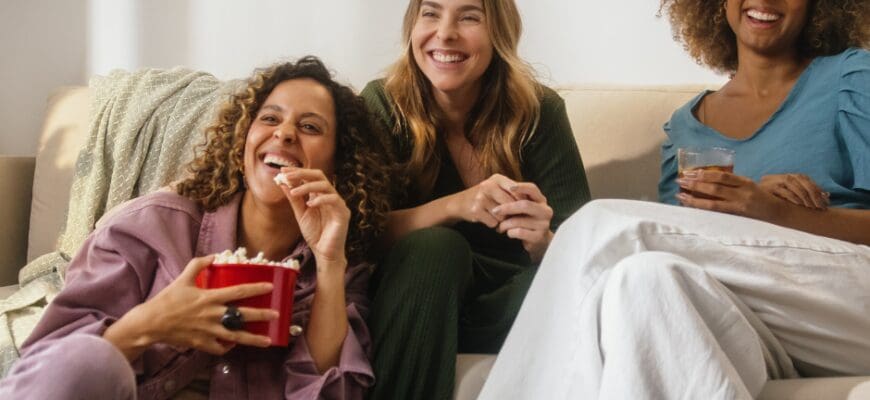 Three woman sitting in a living room with a bowl of snacks